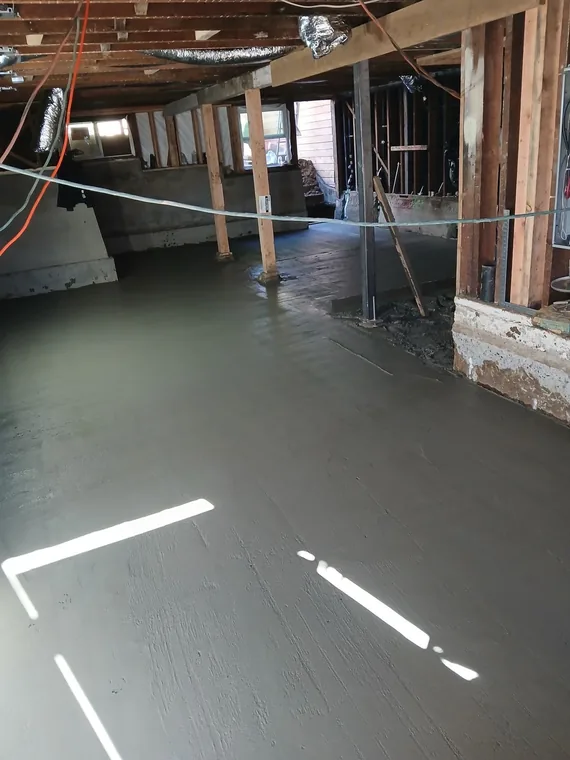 Fresh concrete floor surface beneath exposed framing and timber posts