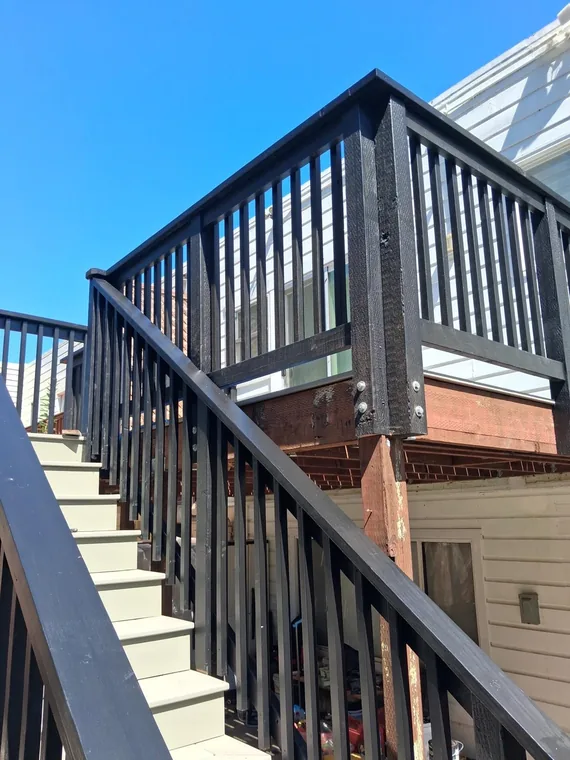 Exterior stair landing with black railings and gray treads