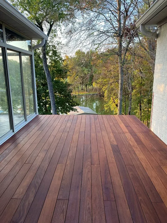 Finished wood deck beside a home with a wooded view