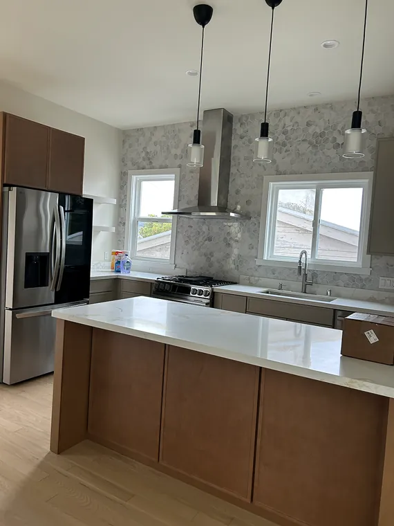Finished kitchen with wood cabinetry, stone counters, and hexagonal tile