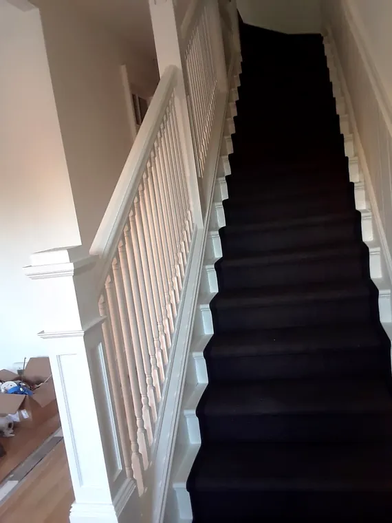 Finished interior staircase with dark treads and white railing