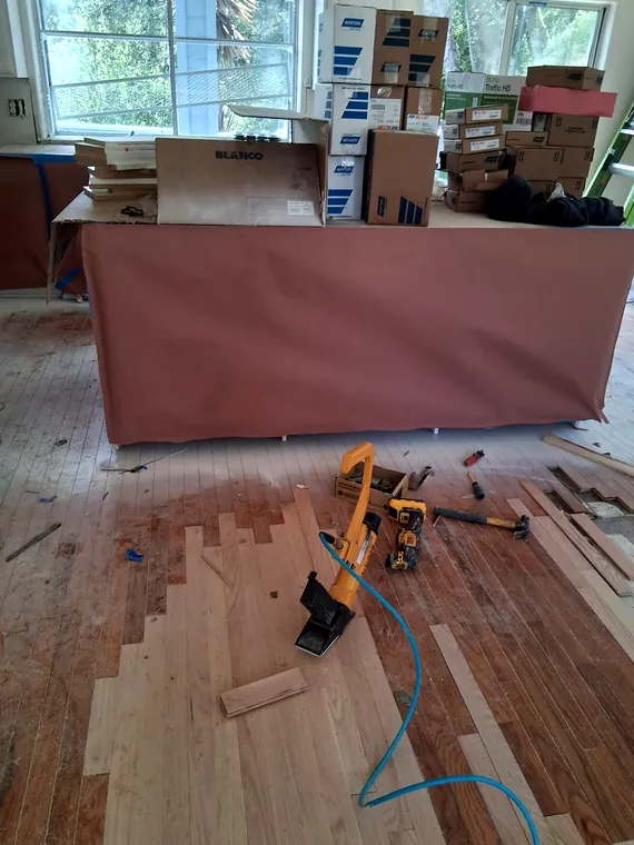 Wood flooring installation in progress with tools and materials