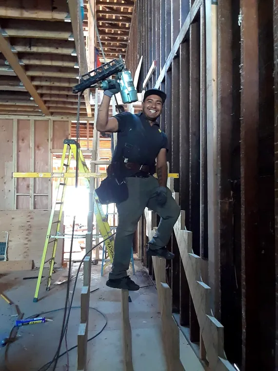 Carpenter working within exposed residential wall framing