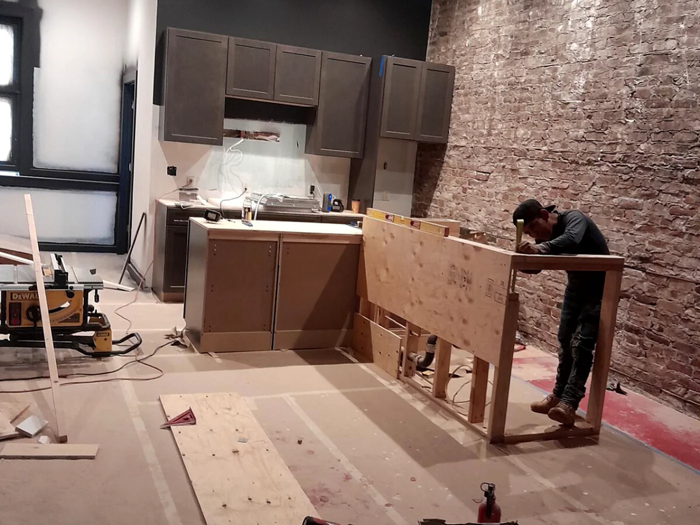 Kitchen installation in progress with cabinetry and exposed brick wall