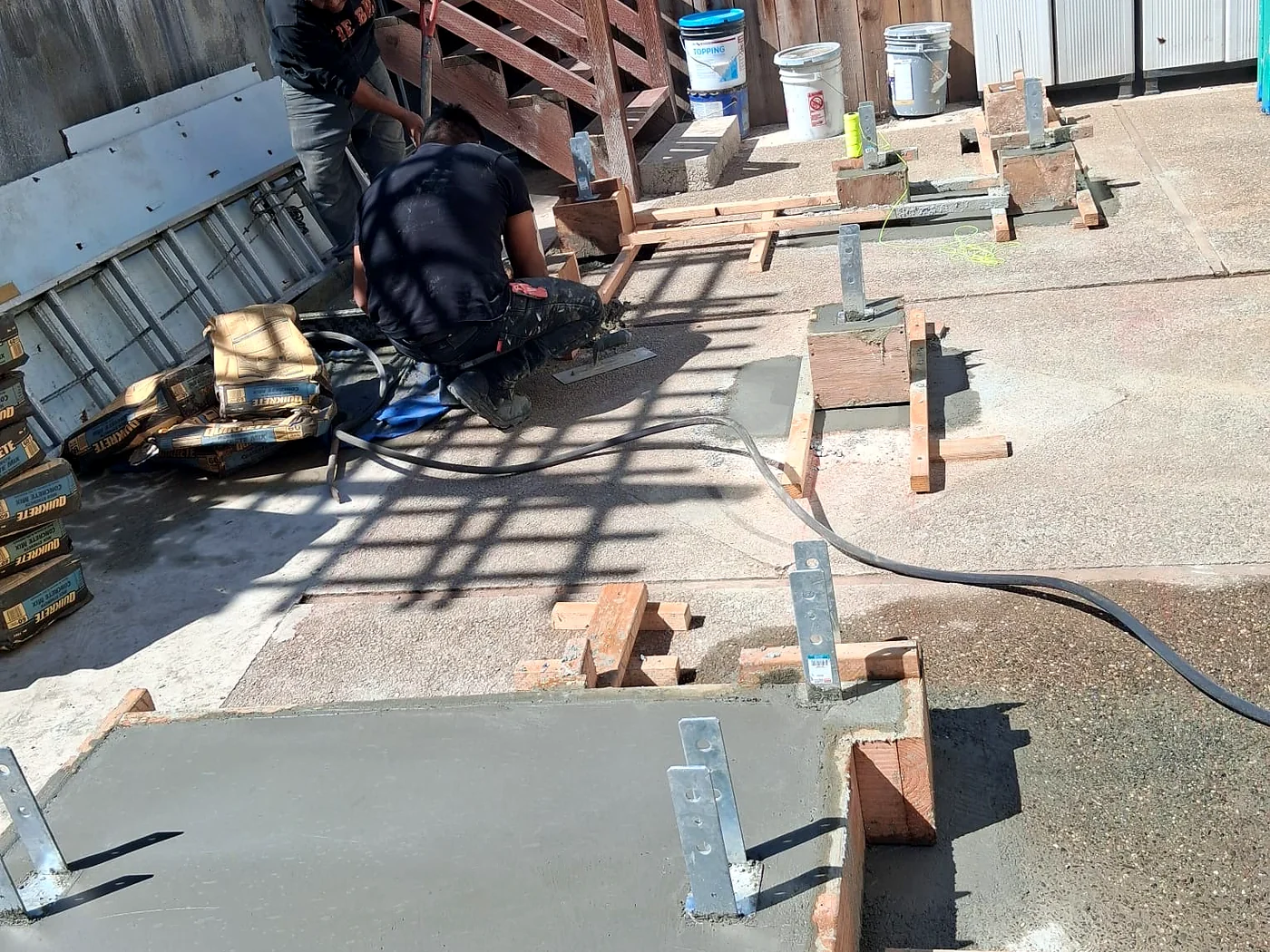 Worker forming a new concrete footing beside an exterior stair